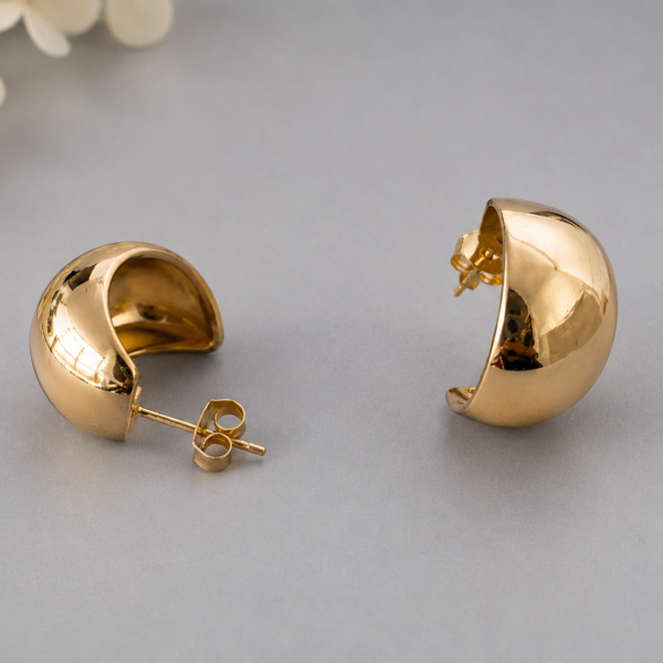 Chunky gold half hoop earrings with polished mirror finish displayed on a neutral background.