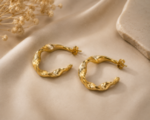Twisted gold hoop earrings with organic sculptural design and polished gold-tone finish on a neutral background.