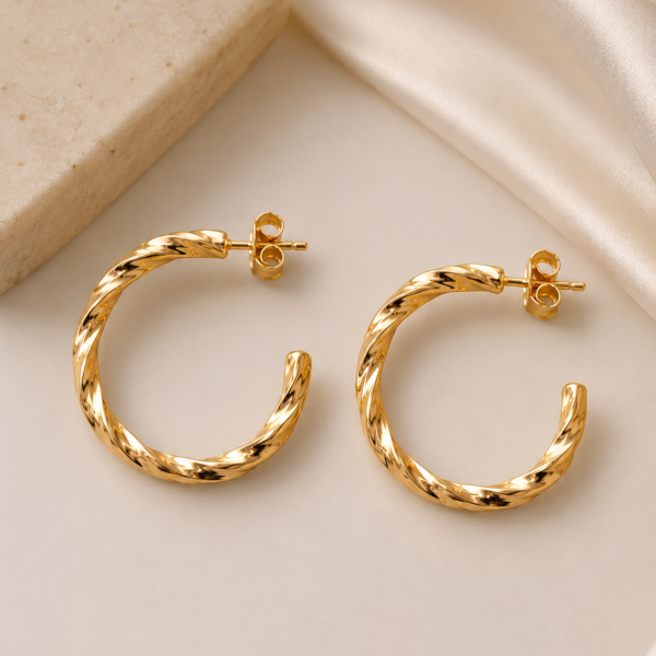 Twisted gold hoop earrings with rope-texture design and polished gold-tone finish worn by a female model.