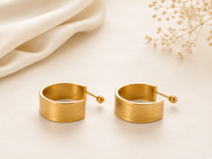 Gold wide cuff hoop earrings with brushed gold finish on a soft neutral background.