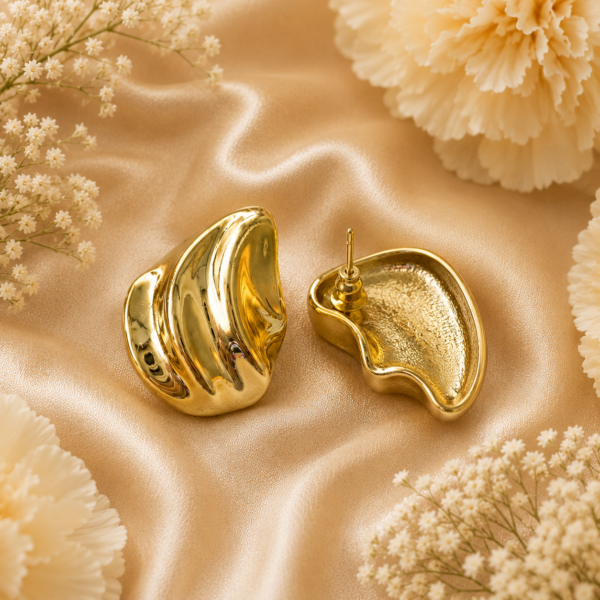 Abstract sculptural gold statement stud earrings with polished organic design on satin background.