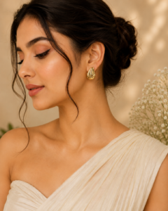 Abstract sculptural gold statement stud earrings with polished organic design on satin background.