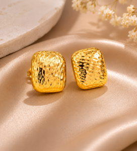 Fashion model wearing textured hammered gold square stud earrings in a luxury beauty photoshoot.