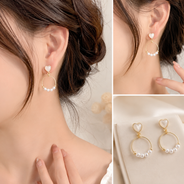Gold-tone heart stud hoop earrings with pearl accents displayed on a white jewelry card in a soft luxury setting.