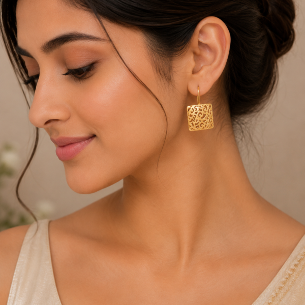 Woman wearing elegant gold filigree drop earrings with intricate openwork detailing and a premium gold-plated finish.