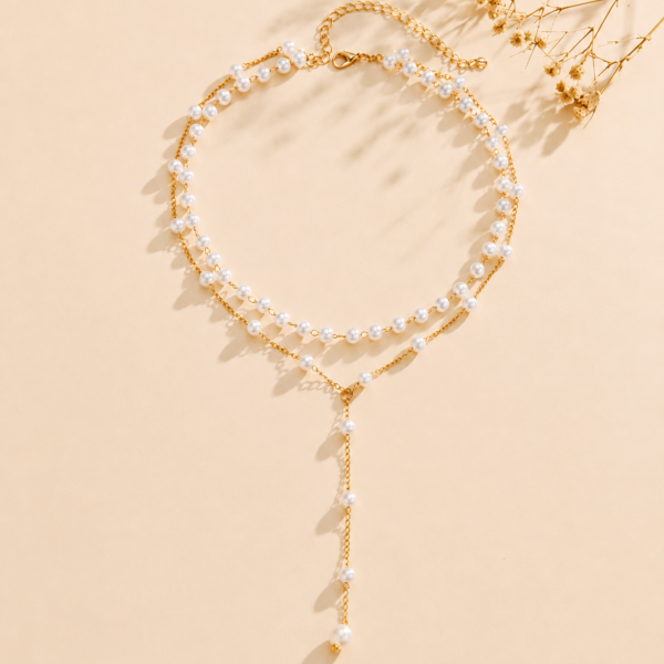 Luxury multi-layer pearl necklace with silver-tone accent beads and a crystal drop pendant displayed in an elegant flat-lay product photography setting.