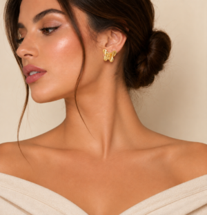 Woman wearing elegant gold butterfly stud earrings with textured wing detailing and a polished finish.