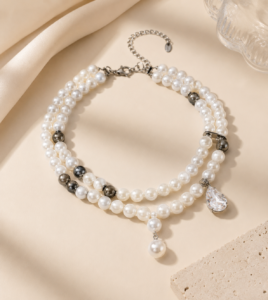 Luxury double-layer pearl choker necklace with metallic accent beads and a crystal drop pendant displayed in an elegant flat-lay product photography setup.
