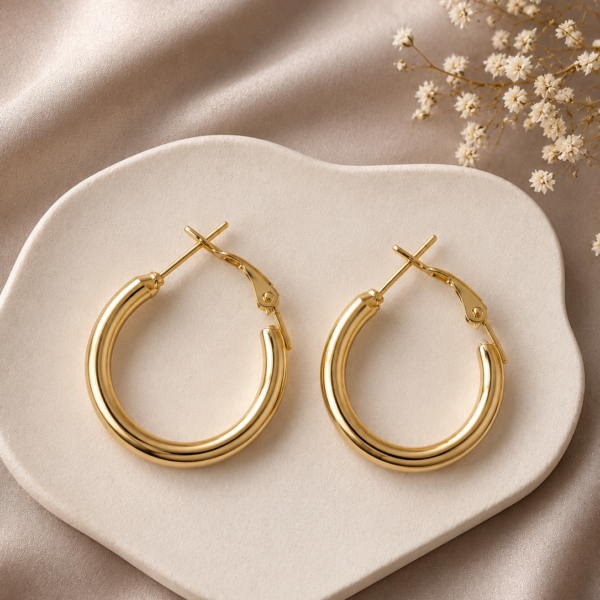 Classic gold hoop earrings with a polished finish displayed on a neutral ceramic tray.