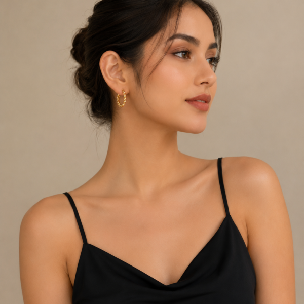 Elegant gold twisted hoop earrings with braided rope detailing displayed on a neutral stone background.