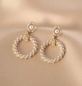 Fashion model wearing luxury pearl crystal hoop earrings with gold-tone detailing in a professional beauty photoshoot