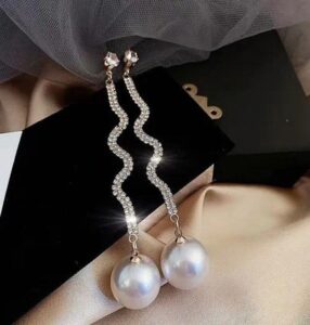 Woman wearing elegant gold pearl drop earrings with a modern gold-plated design and white pearl accents.
