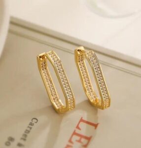 Woman wearing luxury gold-tone crystal hoop earrings with sparkling stone detailing