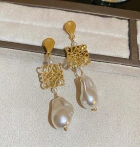 Woman wearing elegant gold pearl drop earrings with a modern gold-plated design and white pearl accents.