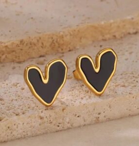 Woman wearing black & White heart-shaped enamel stud earrings with gold-tone border