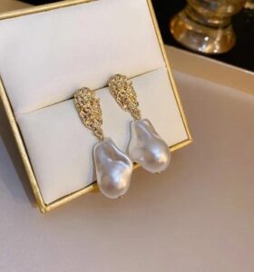 Woman wearing elegant gold pearl drop earrings with a modern gold-plated design and white pearl accents.