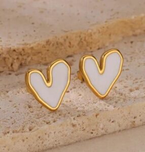 Woman wearing black & White heart-shaped enamel stud earrings with gold-tone border
