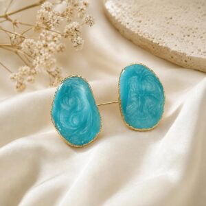 Elegant turquoise blue oval statement stud earrings with a gold finish displayed on a luxury satin background.